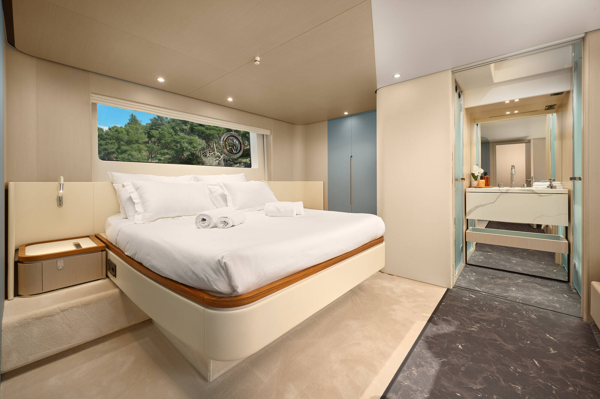 Full-beam master cabin with a blue-accent dressing area, hull windows and a private en-suite
